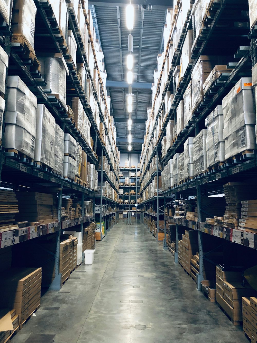 Corredor de depósito com prateleiras altas de estoque paletizado